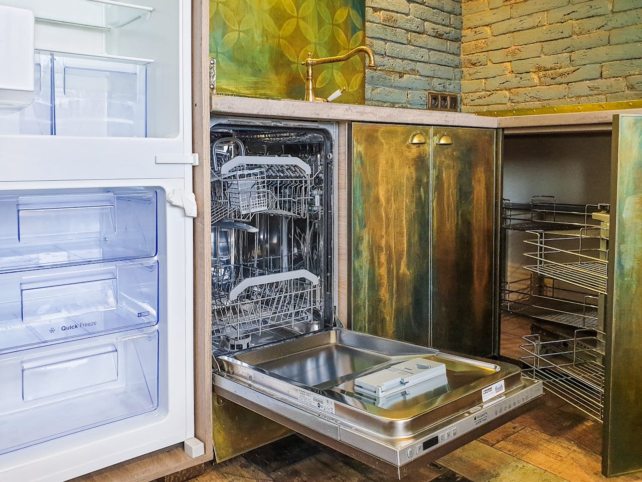 A contemporary kitchen showcasing a neat, open dishwasher beside an empty refrigerator.